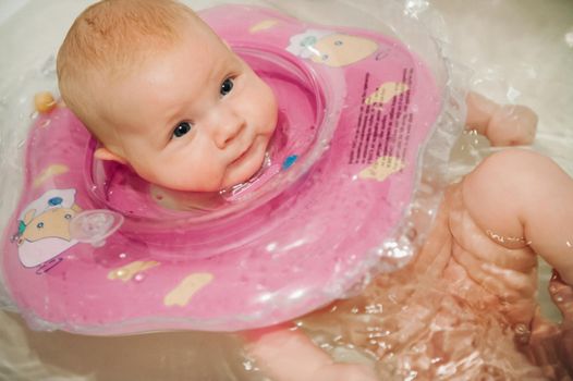 a small child washes his head in the bath.A little girl is lying in the bathroom with a circle.