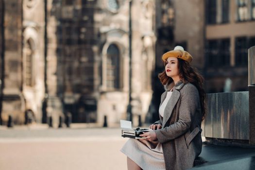 a stylish young beautiful girl is sitting and typing in the Old town of Dresden.Germany