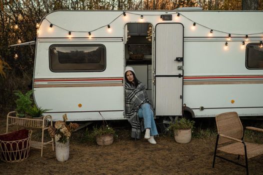 Caucasian woman sits in a van on a warm autumn day. Travel in a camper