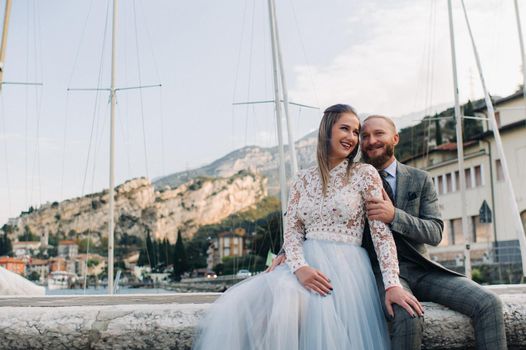 Italy, Lake Garda. A beautiful couple on the shores of lake Garda in Italy at the foot of the Alps.A man and a woman sit on a pier in Italy.