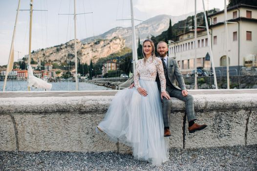 Italy, Lake Garda. A beautiful couple on the shores of lake Garda in Italy at the foot of the Alps.A man and a woman sit on a pier in Italy.