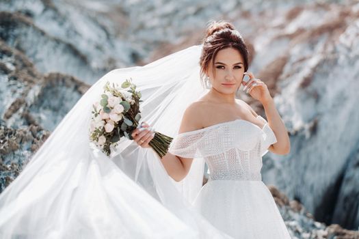 Beautiful bride in a wedding dress with a bouquet on the top of the salt mountains. A stunning young bride with curly hair . Wedding day. . Beautiful portrait of the bride without the groom