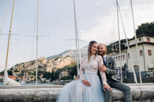 Italy, Lake Garda. A beautiful couple on the shores of lake Garda in Italy at the foot of the Alps.A man and a woman sit on a pier in Italy.