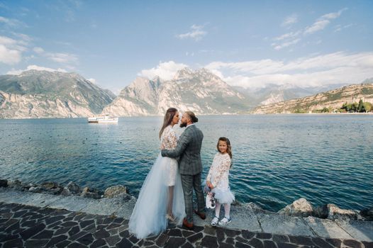 Italy, Lake Garda. Beautiful family on the shores of lake Garda in Italy at the foot of the Alps. Father, mother and daughter in Italy.