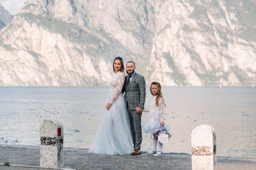 Italy, Lake Garda. Beautiful family on the shores of lake Garda in Italy at the foot of the Alps. Father, mother and daughter in Italy.