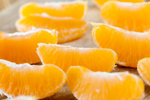 juicy mandarin peeled from the rind, folded in rows on an old wooden board, photo closeup of juicy citrus fruit, divided into small slices