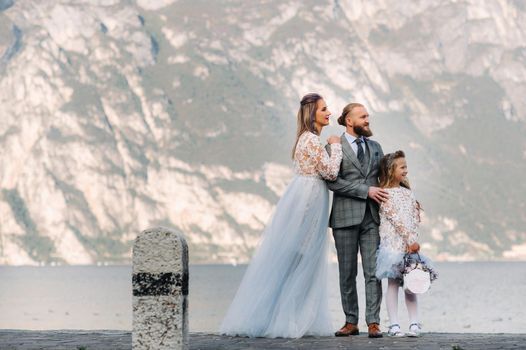 Italy, Lake Garda. Beautiful family on the shores of lake Garda in Italy at the foot of the Alps. Father, mother and daughter in Italy.