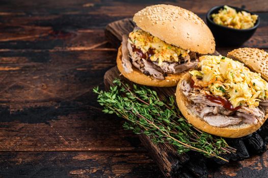 Pulled pork burger with bbq sauce and coleslaw salad. Dark wooden background. Top view. Copy space.