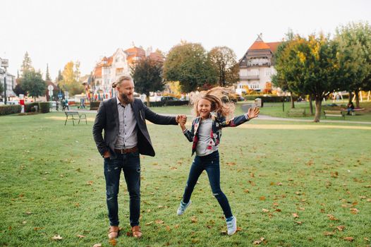 Father and daughter running on the grass in the old town of Austria.A family walks through a small town in Austria.Europe.Felden am Werten see.