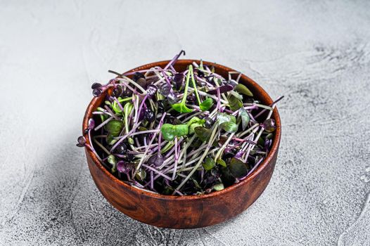 Microgreen radish cress sprouts in a wooden bowl. White background. Top view.