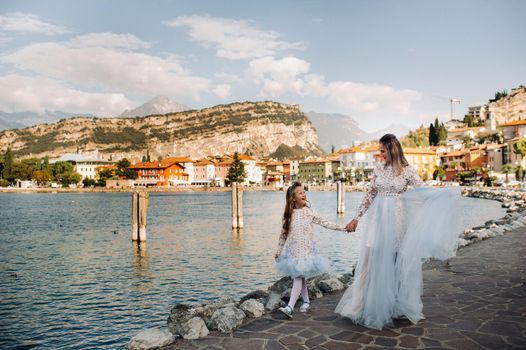 Italy, Lake Garda.Stylish Mother and daughter on the shores of lake Garda in Italy at the foot of the Alps. mother and daughter in Italy.