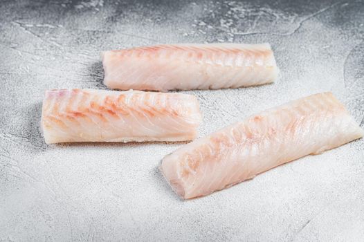 Raw Norwegian cod fish fillet on kitchen table. White background. Top view.