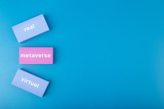 Metaverse modern minimal concept in blue colors with copy space. Written metaverse, real, virtual words on blue and pink rectangles against blue background. Future technologies. 