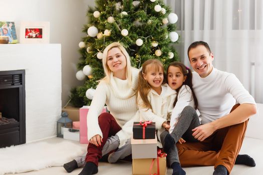 happy young family holding christmas gift and smiling at camera