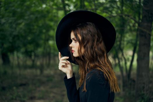 woman witch in black hat in the forest posing fantasy. High quality photo