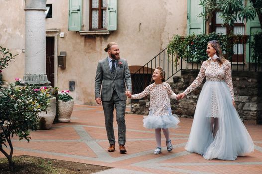 A happy young family walks through the old town of Sirmione in Italy.Stylish family in Italy on a walk.