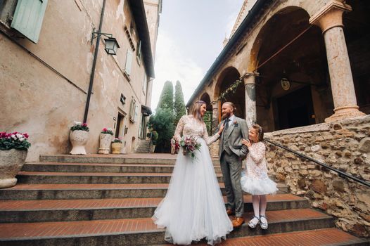 A happy young family walks through the old town of Sirmione in Italy.Stylish family in Italy on a walk.