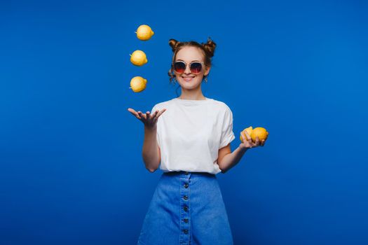 Beautiful bright girl in retro style, throws up yellow lemons. Happy girl,
