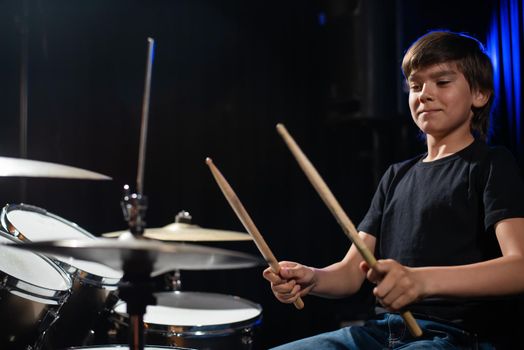 A boy plays drums in a recording studio.