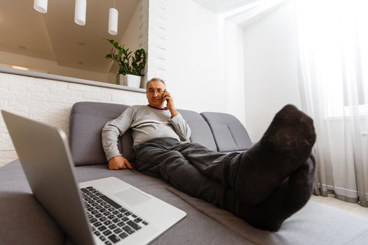 Senior man in sofa with laptop computer