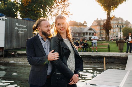 a family of two stands on a pier in Austria's old town at sunset .A man and a woman embrace on the embankment of a small town in Austria.Europe.Felden am Werten see.