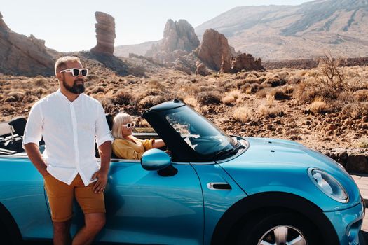 a woman and a man wearing glasses in a convertible car on a trip to the island of Tenerife. The crater of the Teide volcano, Canary Islands,Spain.