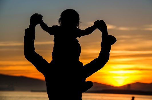 Silhouette of mother which her child against a sunset