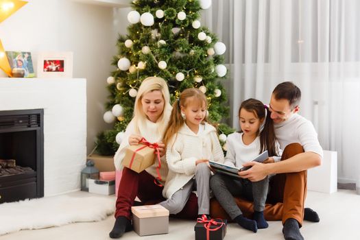 happy family father mother and children sitting by fireplace on Christmas Eve