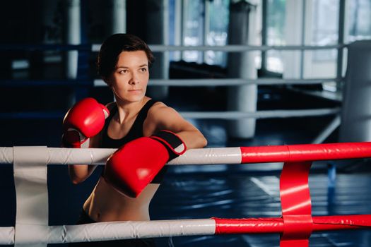 portrait of a female boxer in red gloves in the gym during training.