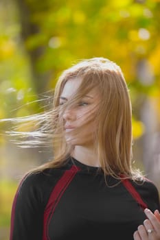 Portrait of Young attractive female at workout in autumn park - waving blond hair, close up