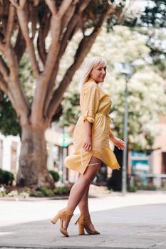 a blonde woman in a yellow summer dress stands on the street of the Old town of La Laguna on the island of Tenerife.Spain, Canary Islands.