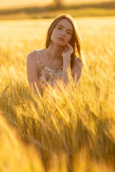 Girl in a dress in a wheat field at sunset.