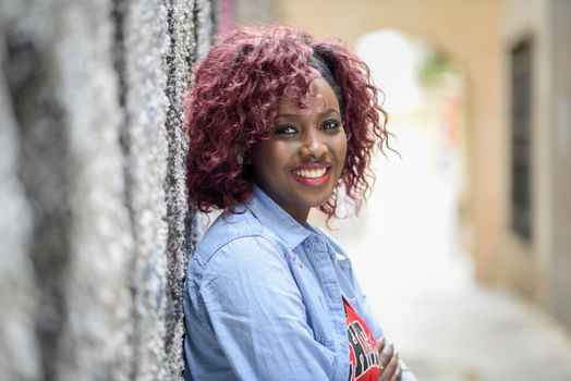 Happy young black woman in urban background with red hair wearing casual clothes