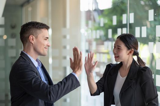 Business man and woman business hi five bump hand together for team work, diversity caucasian asd asian business team concept