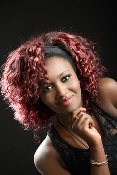 Portrait of beautiful black woman on black background with red hair. Afro hairstyle. Studio shot