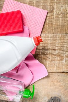 Pink domestic supplies for spring cleaning service. wooden background. Top view.