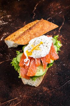 Poached egg with smoked salmon and avocado on toast. Dark background. Top view.