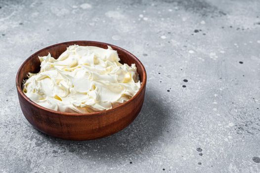 Traditional Mascarpone cheese in wooden bowl. Gray background. Top view. Copy space.