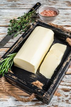 Butter Margarine block in a wooden tray with herbs. White wooden background. Top view.