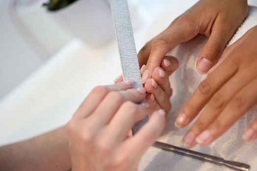 Manicure nail care for the client sitting at a table in the office. Beauty and Aesthetic concepts.