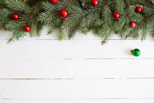 Christmas and New Year background. Fir tree branches with red christmas balls on white wooden bacground .