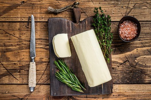 Butter sliced Spread block on a wooden board with herbs. wooden background. Top view.