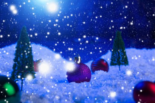 Christmas background with Christmas balls on snow over fir-tree, night sky and moon. Shallow depth of field. Christmas background. Fairy tale. Macro. Artificial magic dreamy world. .