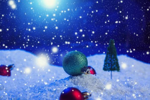 Christmas background with Christmas balls on snow over fir-tree, night sky and moon. Shallow depth of field. Christmas background. Fairy tale. Macro. Artificial magic dreamy world. .