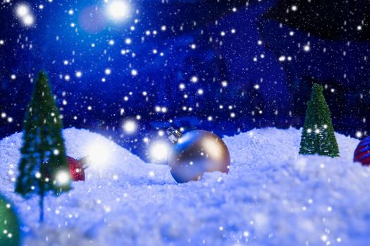 Christmas background with Christmas balls on snow over fir-tree, night sky and moon. Shallow depth of field. Christmas background. Fairy tale. Macro. Artificial magic dreamy world. .