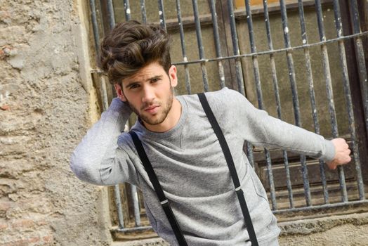 Portrait of young man wearing suspenders in urban background