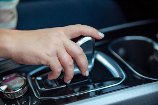 hand switches modes on the automatic transmission lever. close-up. no face. Driver woman hand holding automatic transmission or variable speed drive in car, shifting gear stick before driving car.
