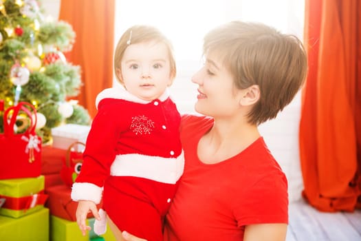 Beautiful young mother and daughter dressed as santa claus enjoying a Christmas day at home together.