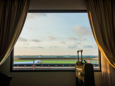 The window of the hotel near the airport on the background of a suitcase or luggage