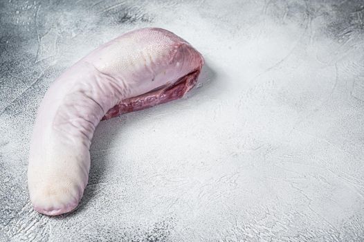 Raw beef tongue on butcher table. White background. Top view. Copy space.